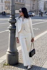 a lady in a white patchwork top, a white jacket and a pair of white pants